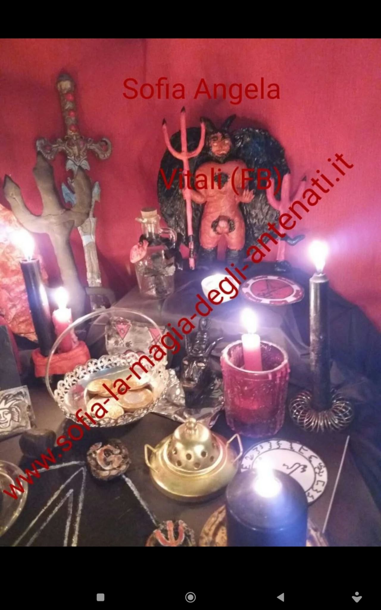 A tabletop arrangement of candles, statues, vessels and decorative objects, framed from above in dim candlelight against a red backdrop.