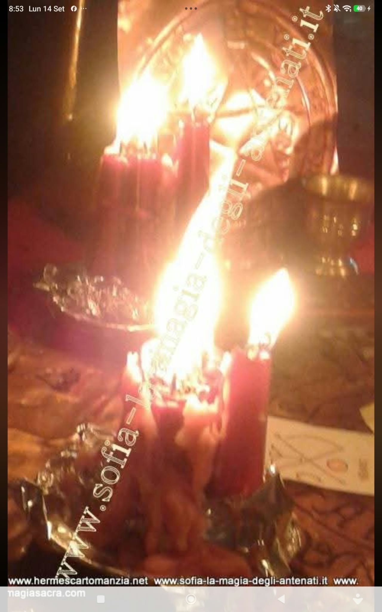 A close-up of clustered red candles and reflective vessels in intense warm light, with a diagonal watermark.