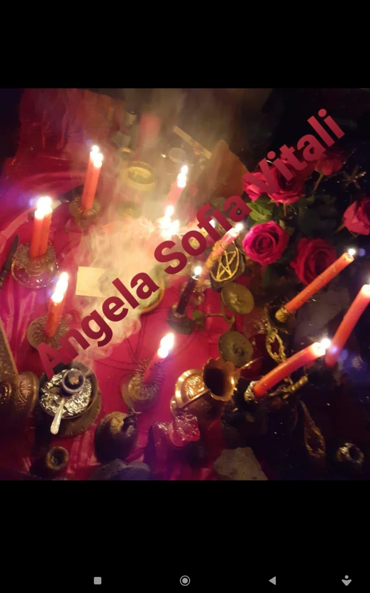 A candlelit tabletop arrangement with red roses, candles and metallic decorative objects, photographed in dim warm lighting.